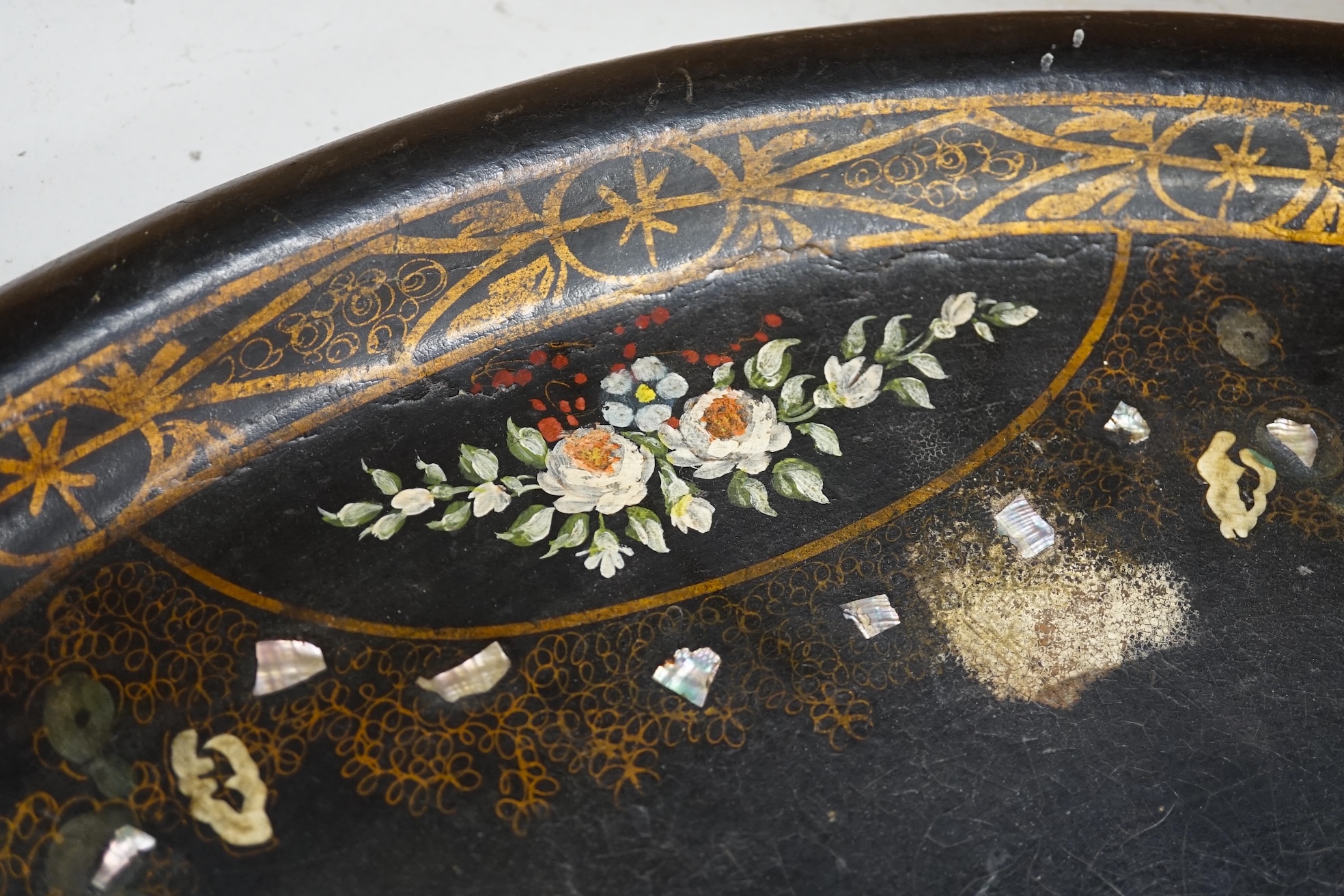 An oval papier mache tray with abalone inlay, hand painted with roses, 75cm wide. Condition - fair